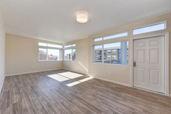 Large Living Room with Wood Inspired Floors, Large White Door, and Open Window at Addison Ranch Apartments, Petaluma, CA, 94954